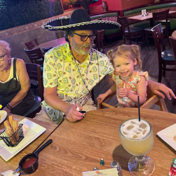 A man in a sombrero and a young girl smiling at a table in Mayan Palace restaurant.
