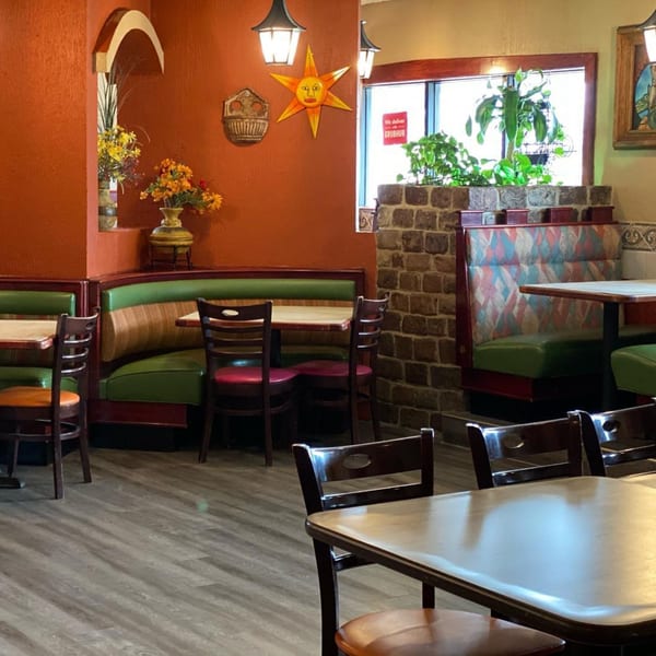 Colorful Mayan Palace dining room with orange walls, green booths, and a sun decoration.