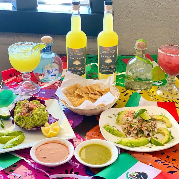 Mayan Palace Mexican food spread with guacamole, ceviche, chips, margaritas, and tequila bottles.