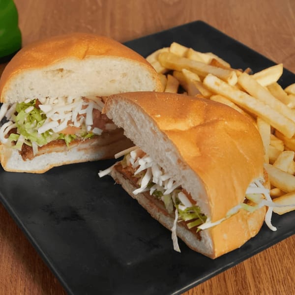 Mayan Palace Mexican torta sandwich, cut in half, with shredded lettuce, cheese, and fries.
